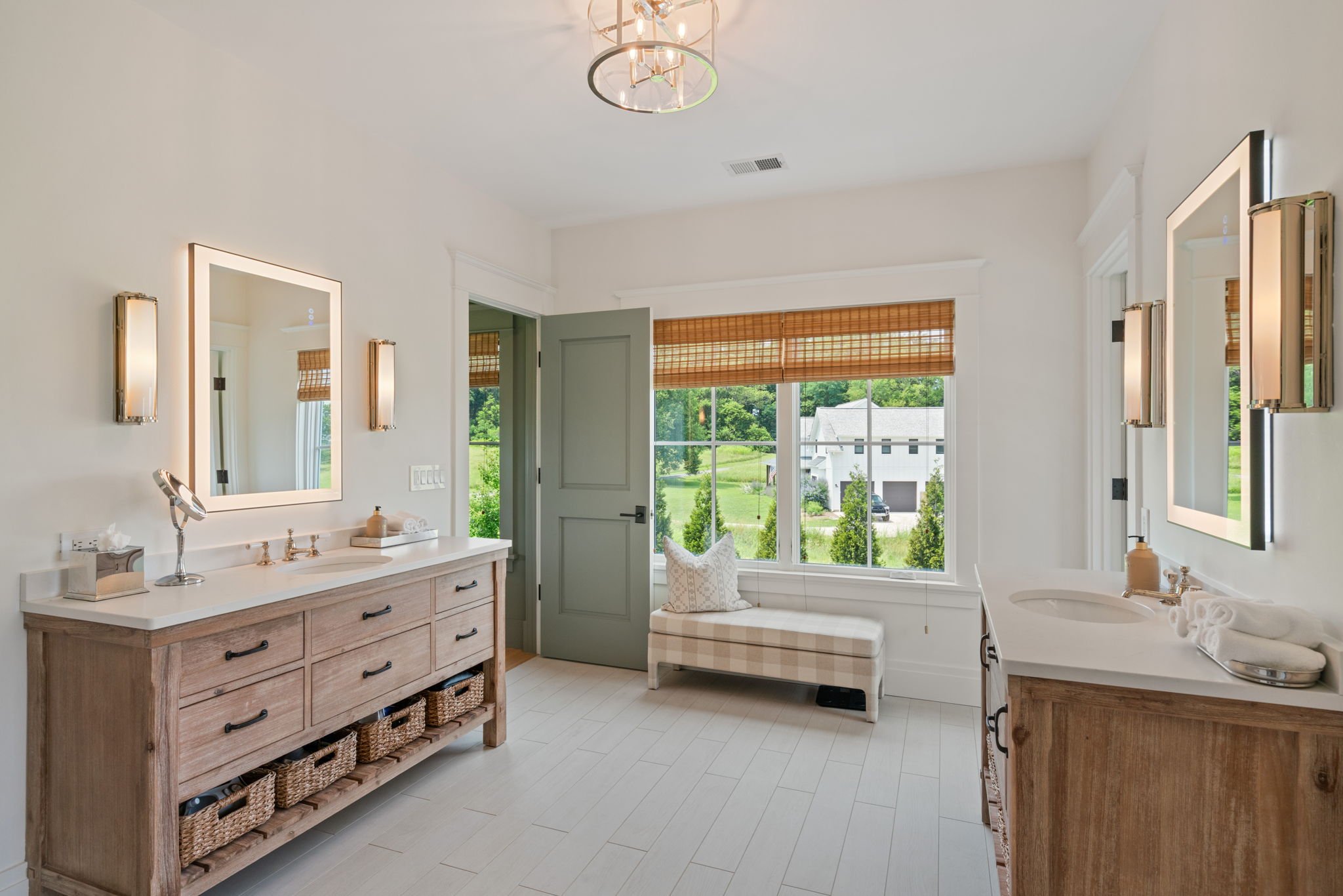 Primary bathroom dressing area with double vanities and window seat