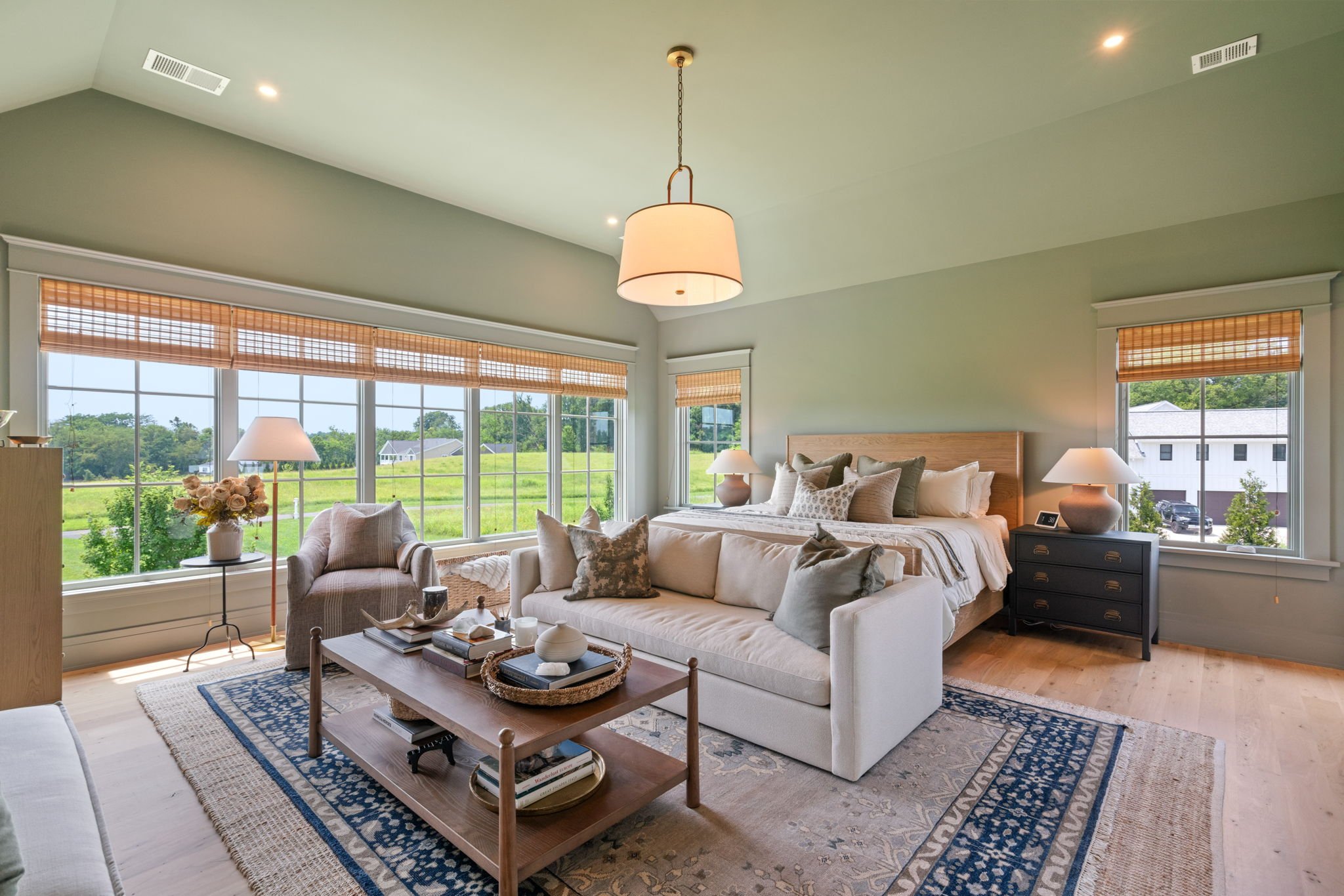 Primary bedroom with vaulted ceiling, sage green walls, and pendant light