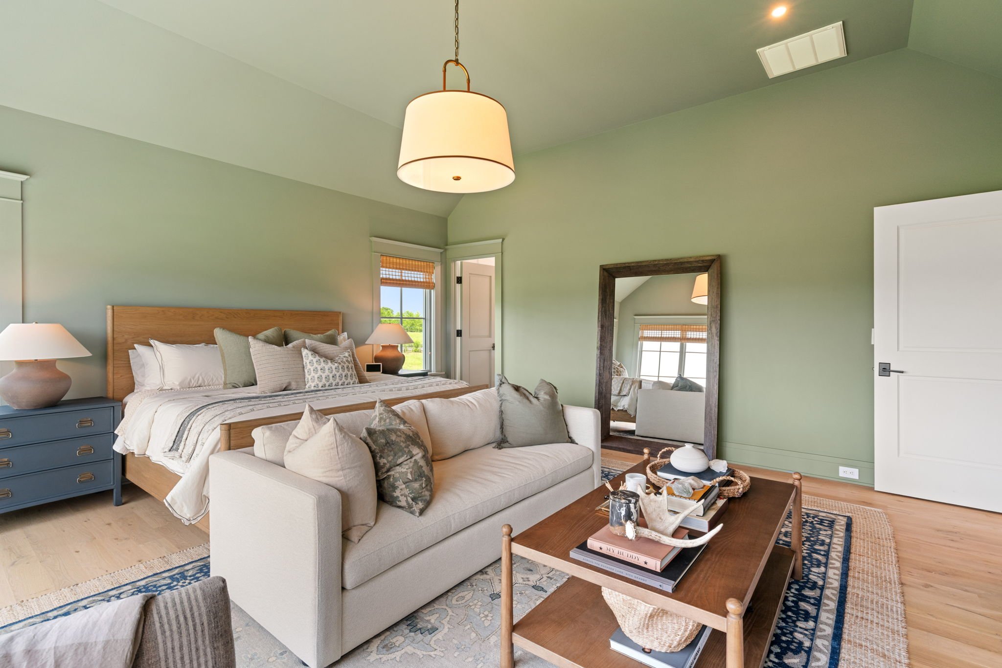 Primary bedroom sitting area with sofa and full-length mirror
