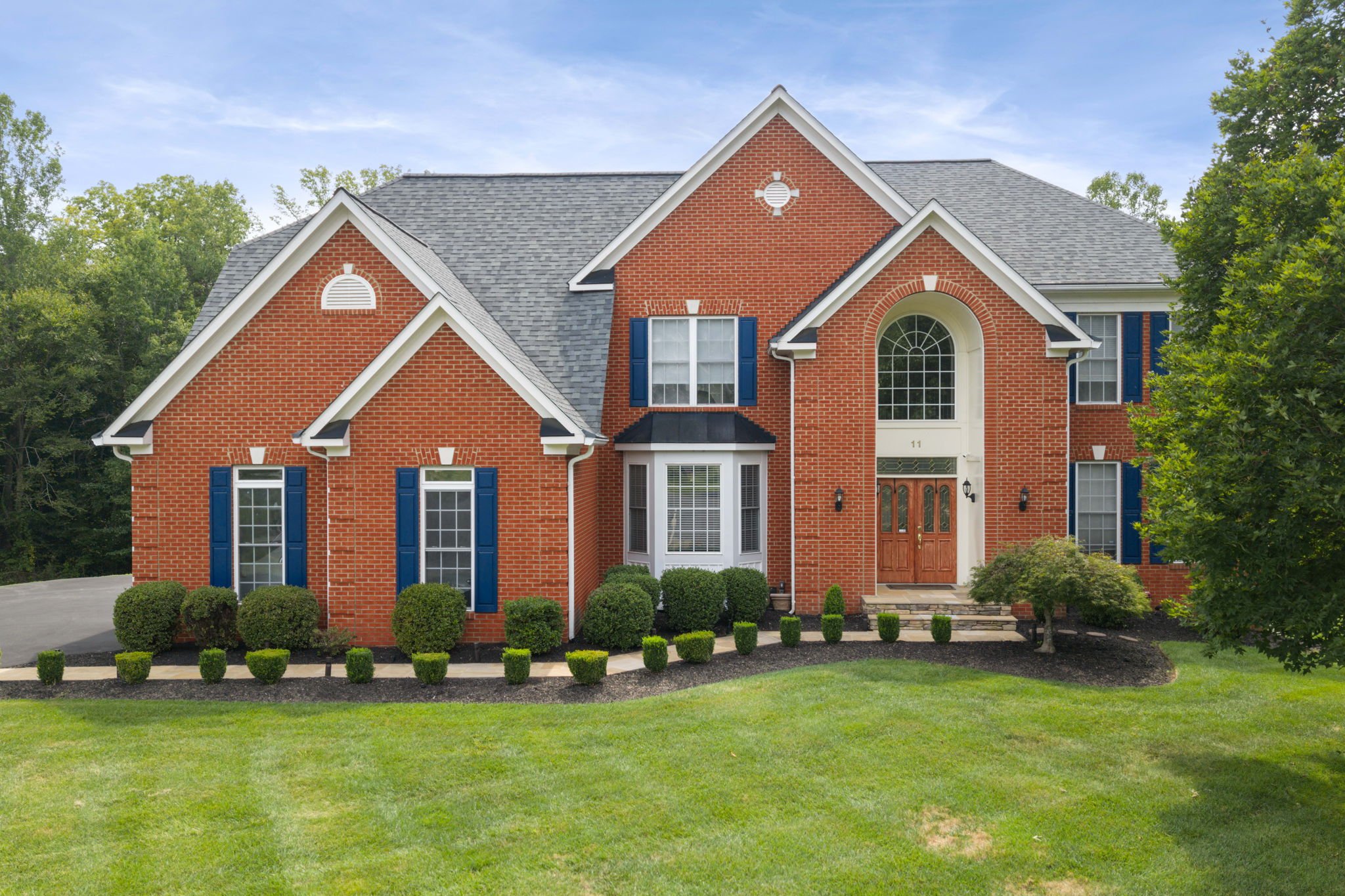 Brick colonial home with blue shutters and manicured landscaping