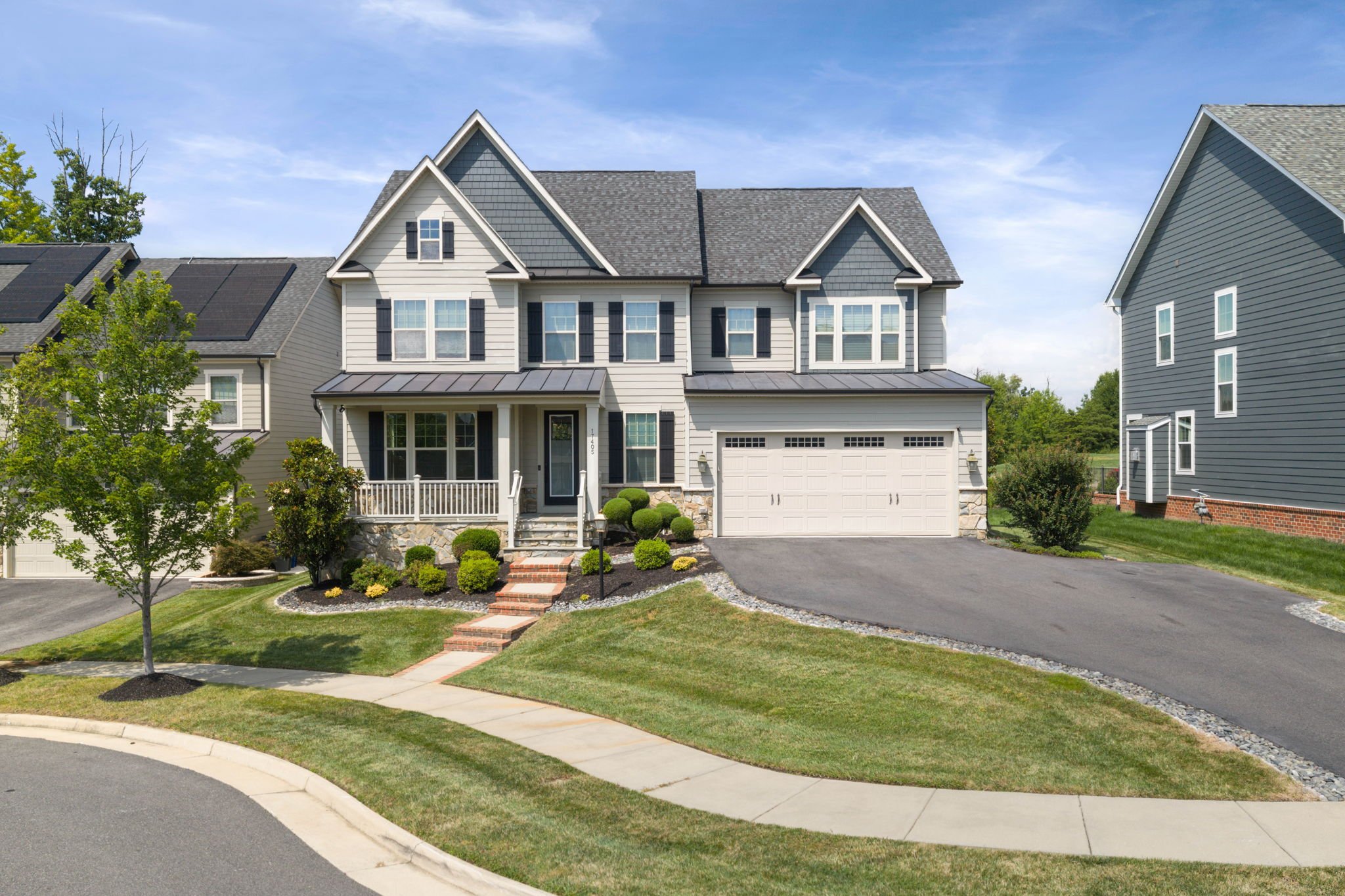Gray craftsman-style home with standing seam metal roof porch and driveway