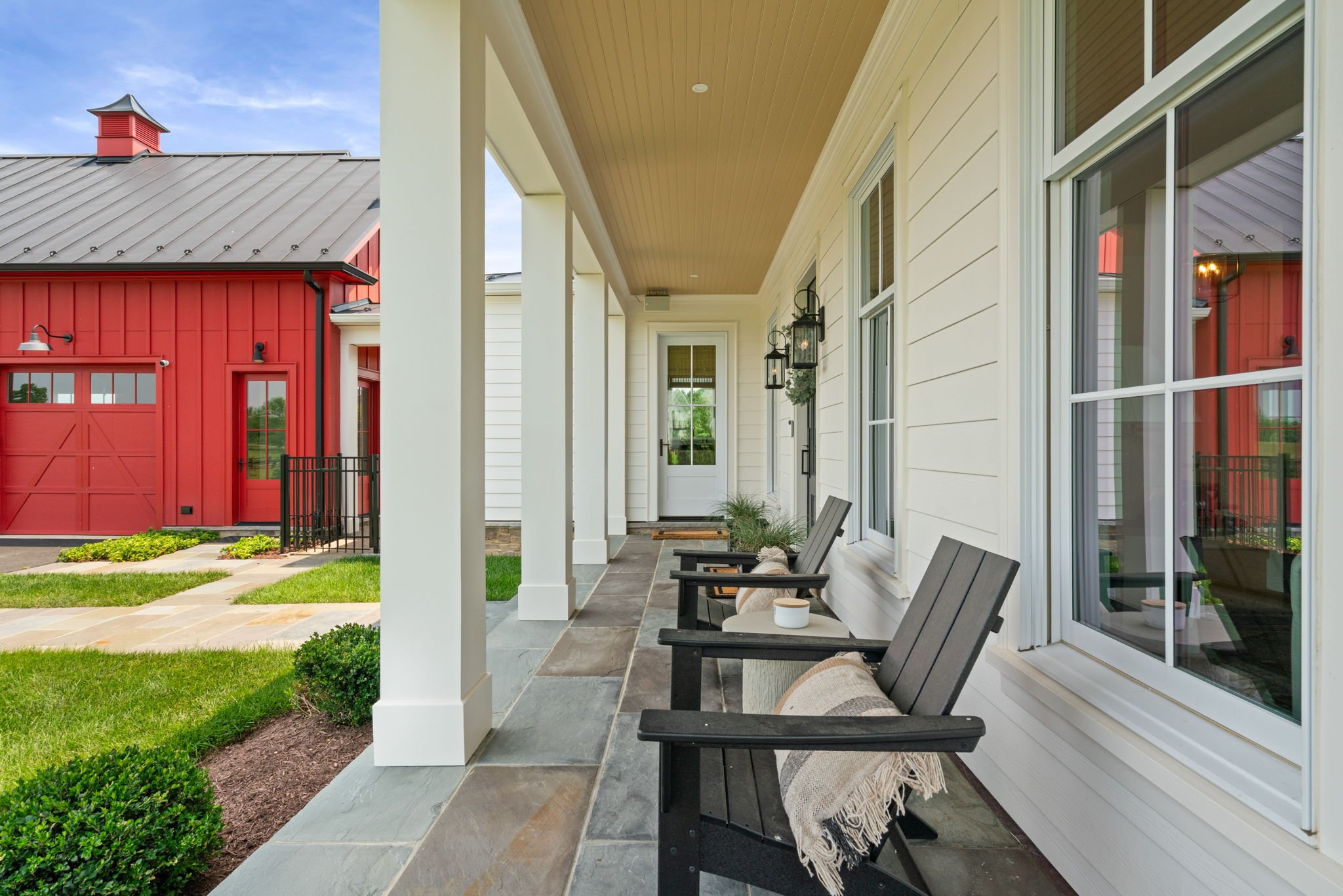 Farmhouse front porch view with matching red barn in the background