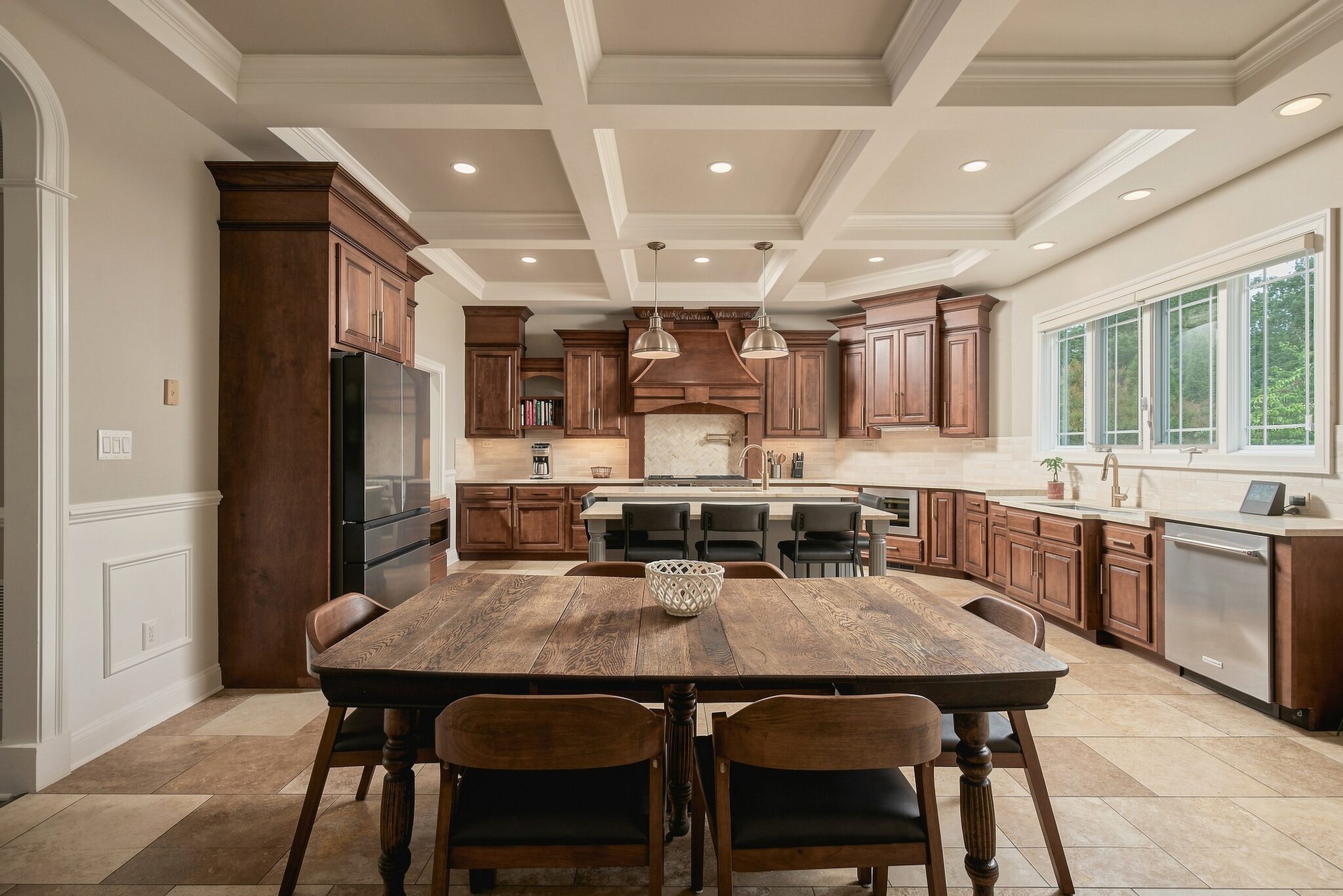 Kitchen and dining area with dark wood cabinetry, coffered ceiling, and a rustic farmhouse table