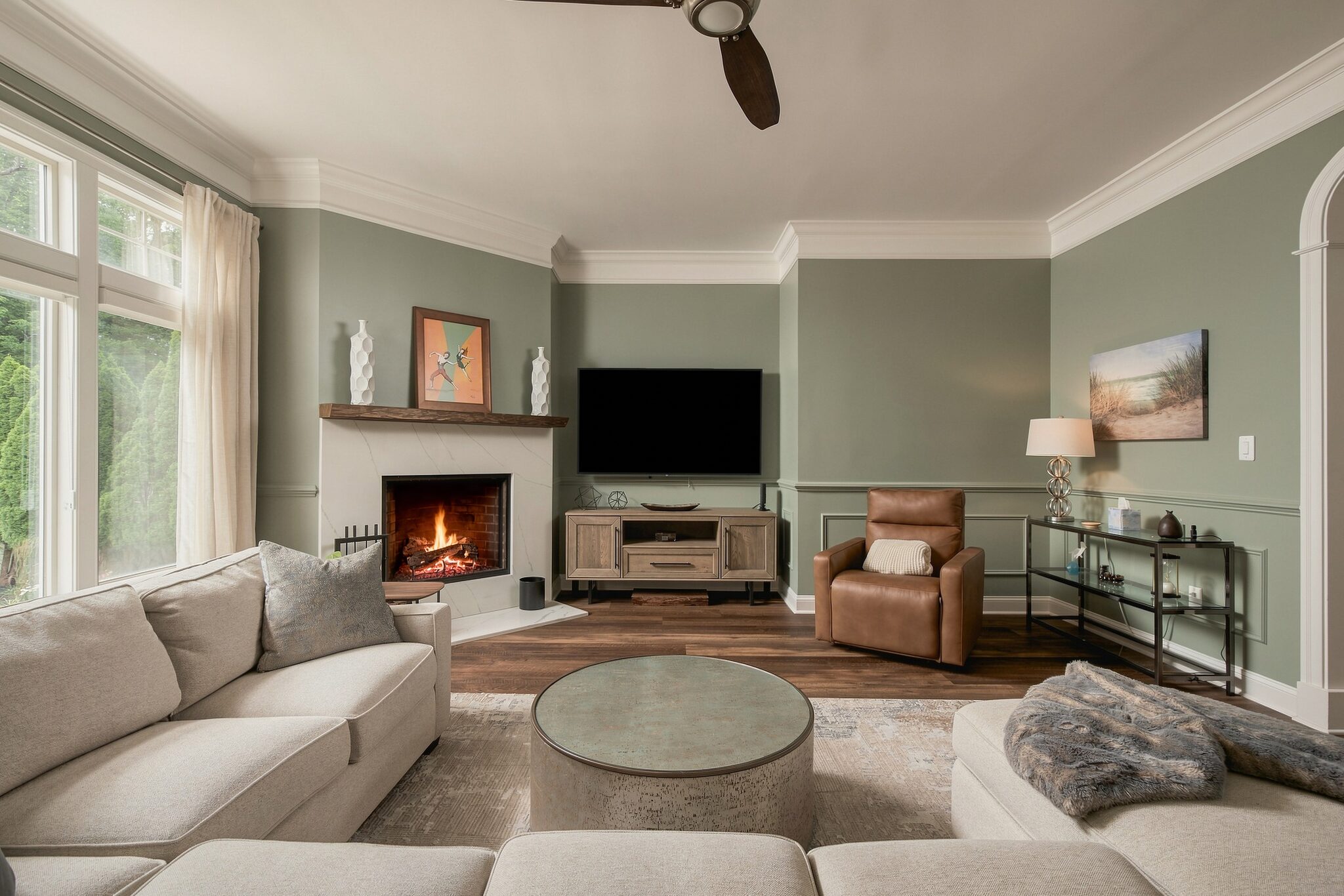 Living room corner with fireplace, TV, and leather recliner beside a tall curtained window
